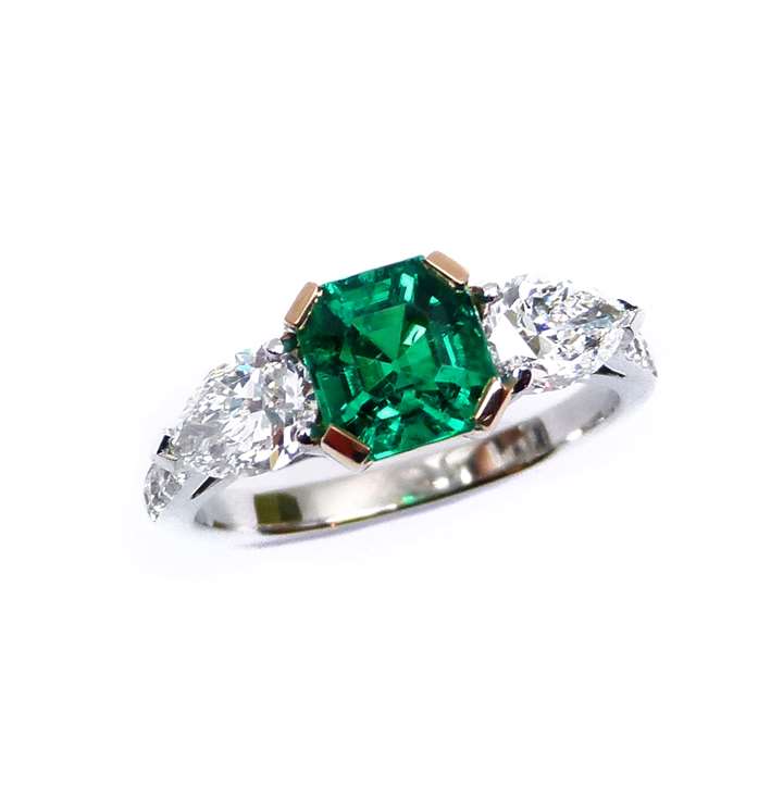 Emerald and diamond three stone ring, centred by a square trap cut emerald, 1.45ct